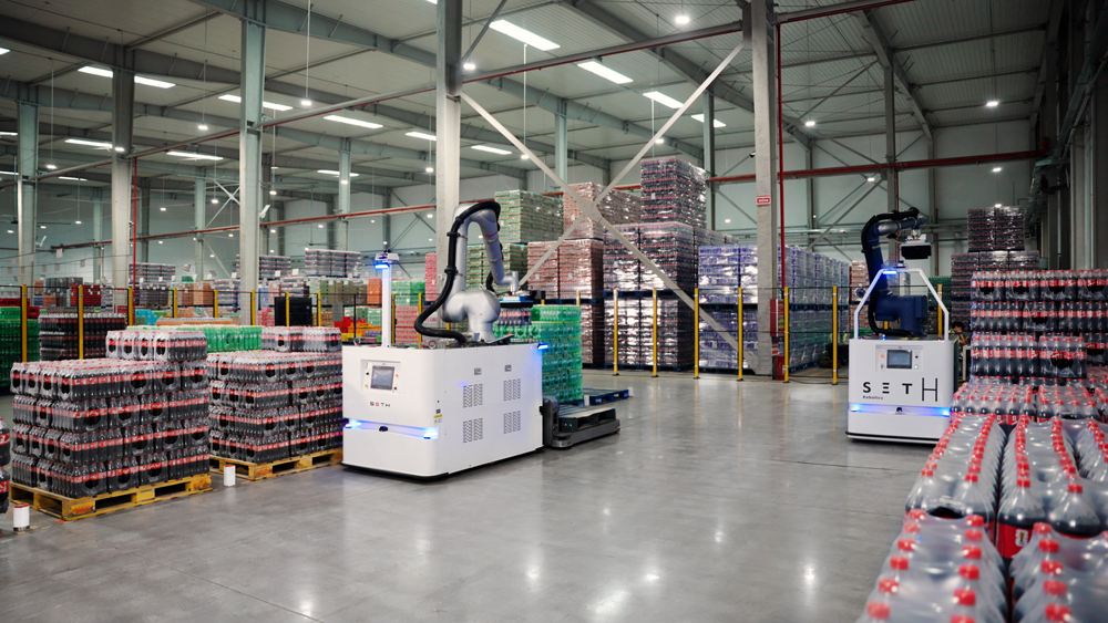 AI-powered picking robots operate among pallets of shrink-wrapped beverages at Swire Coca-Cola’s Zhengzhou plant, supporting the automated preparation of mixed-product orders.